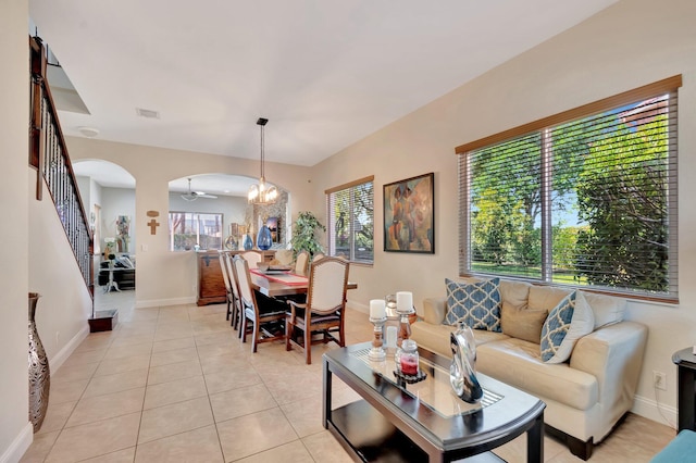 living room with light tile patterned floors, arched walkways, plenty of natural light, and stairs