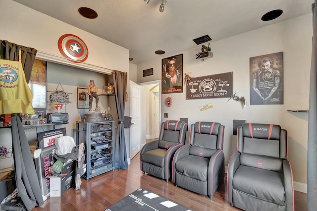 home theater room featuring wood finished floors and visible vents