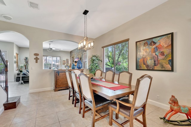 dining space with stairway, light tile patterned floors, visible vents, baseboards, and arched walkways