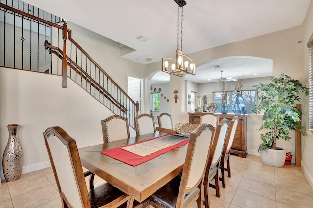 dining space featuring stairs, light tile patterned floors, baseboards, and arched walkways