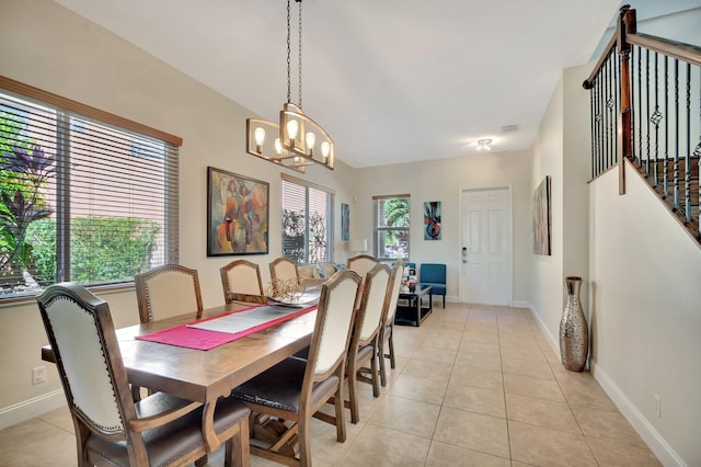 dining space with a notable chandelier, stairway, light tile patterned floors, and baseboards