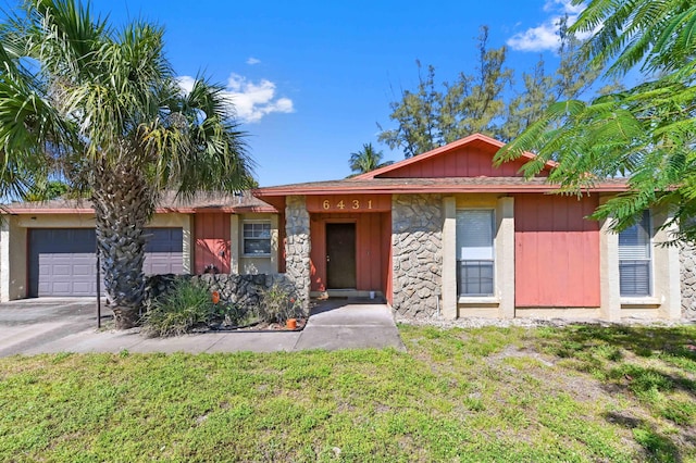 single story home with a garage, stone siding, a front lawn, and driveway