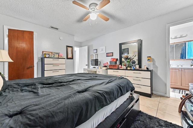 bedroom featuring visible vents, ceiling fan, light tile patterned floors, a textured ceiling, and a sink