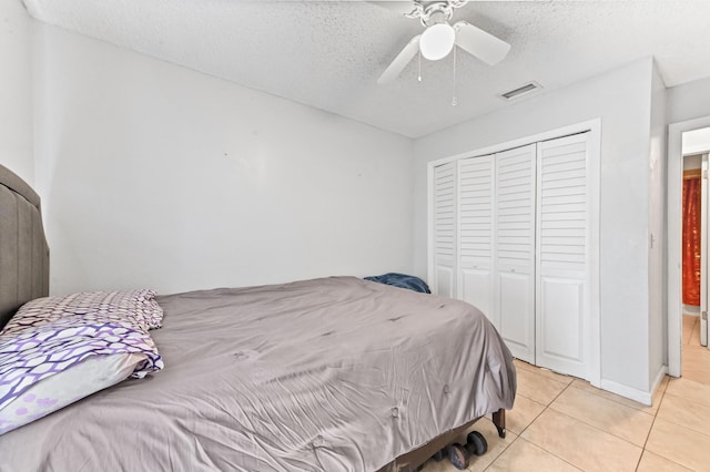 bedroom featuring light tile patterned flooring, visible vents, a textured ceiling, and a closet