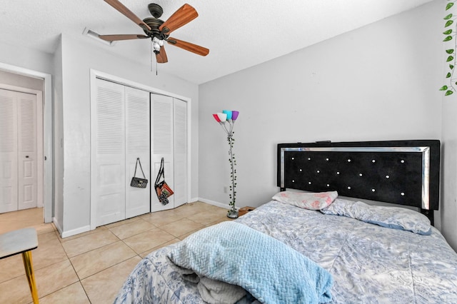 tiled bedroom featuring a closet, baseboards, a textured ceiling, and ceiling fan