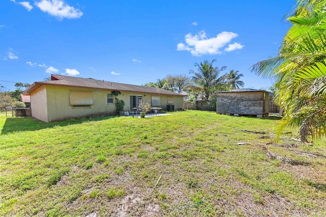 back of house with a patio area, a lawn, a storage shed, a fenced backyard, and an outbuilding