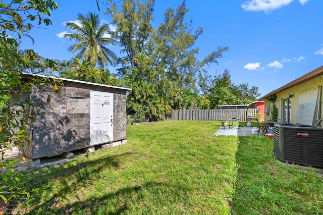 view of yard featuring central AC, a fenced backyard, an outbuilding, a storage unit, and a patio