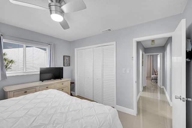 bedroom featuring a closet, visible vents, ceiling fan, light tile patterned floors, and baseboards