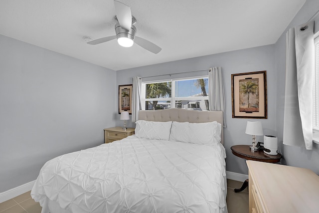 tiled bedroom featuring baseboards and a ceiling fan