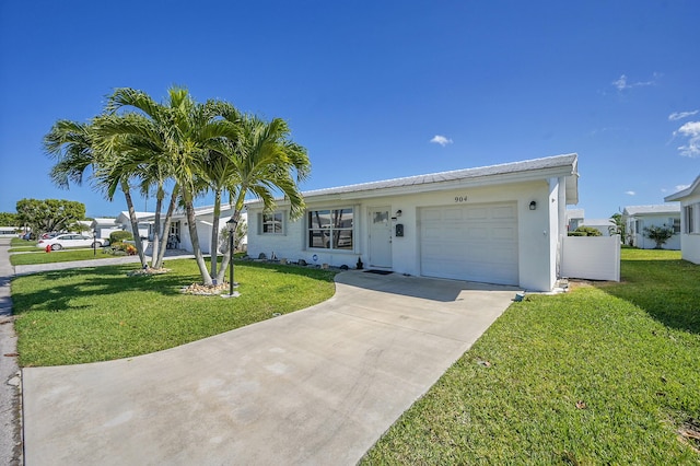 ranch-style house with driveway, stucco siding, an attached garage, and a front yard