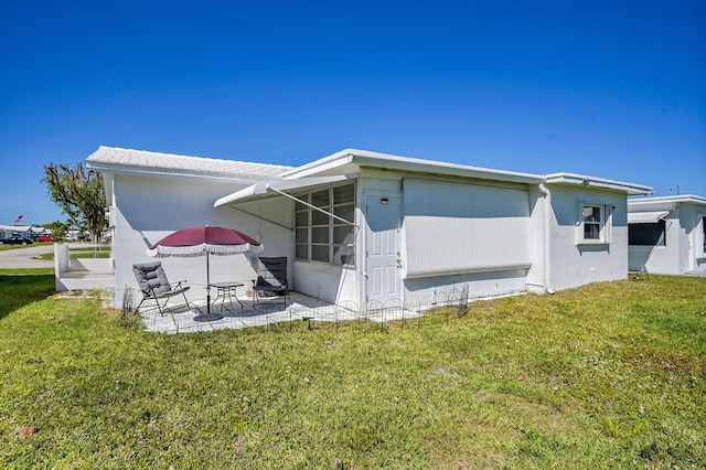 rear view of house with a yard, a patio area, and stucco siding