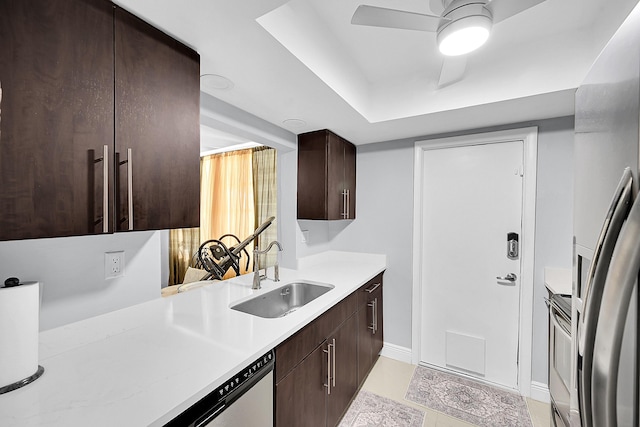 kitchen with freestanding refrigerator, range, a sink, dark brown cabinetry, and light countertops