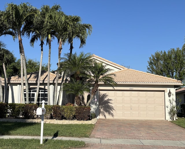 single story home with a tiled roof, a garage, decorative driveway, and stucco siding