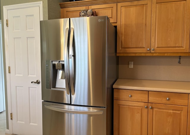 kitchen featuring light countertops, stainless steel fridge with ice dispenser, and brown cabinets