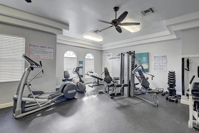 exercise room featuring baseboards, a ceiling fan, visible vents, and a textured ceiling