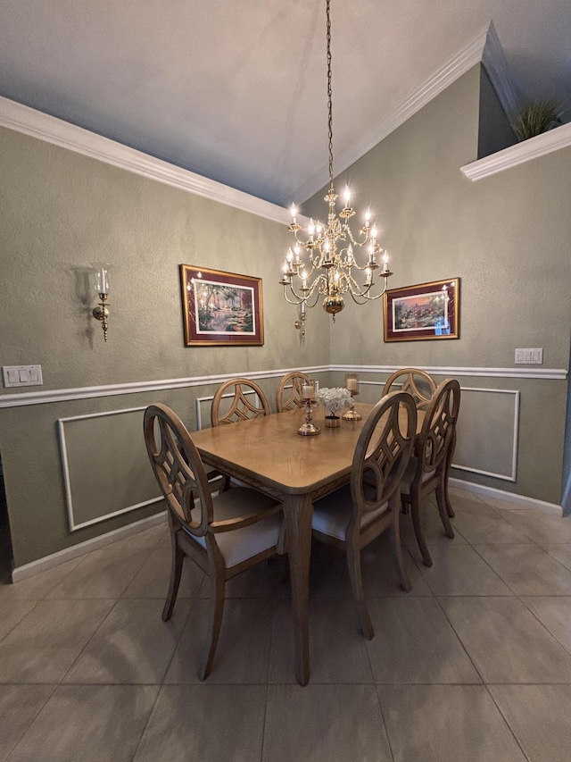 tiled dining space with a wainscoted wall, a notable chandelier, ornamental molding, and vaulted ceiling