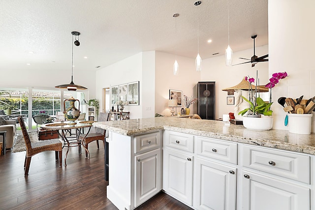 kitchen featuring decorative light fixtures, white cabinets, a textured ceiling, and dark wood-style flooring