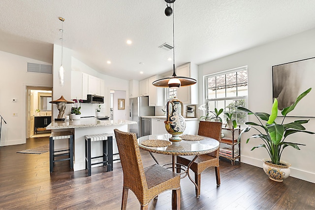 dining room featuring visible vents, a textured ceiling, dark wood finished floors, and vaulted ceiling