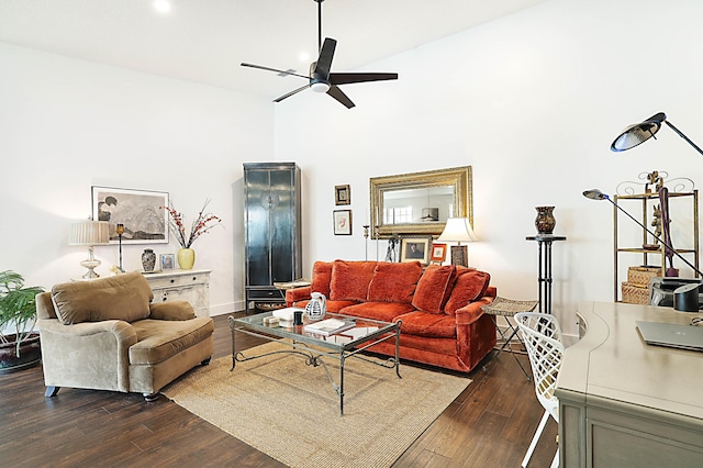 living room featuring a towering ceiling, baseboards, dark wood-style flooring, and a ceiling fan