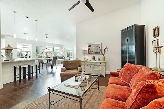 living room featuring dark wood-style floors, a ceiling fan, and baseboards