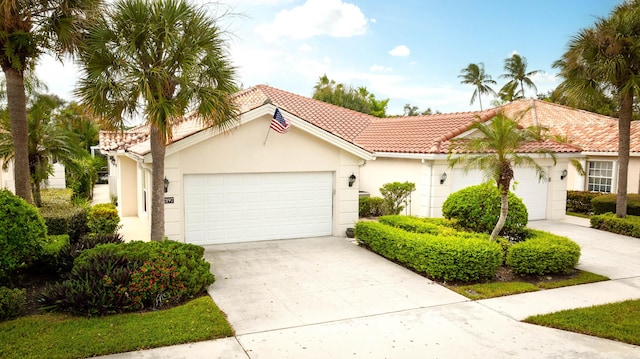 mediterranean / spanish home with a tile roof, an attached garage, driveway, and stucco siding