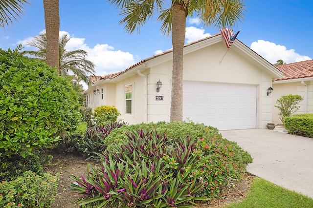 mediterranean / spanish-style house featuring concrete driveway, a tiled roof, an attached garage, and stucco siding