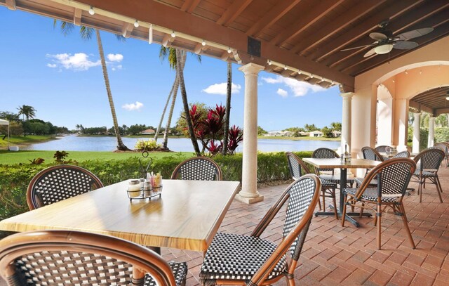 view of patio featuring outdoor dining area, a water view, and a ceiling fan