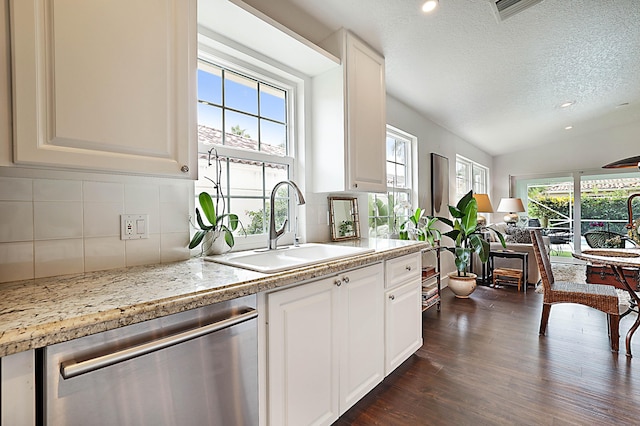 kitchen featuring stainless steel dishwasher, a wealth of natural light, backsplash, and a sink