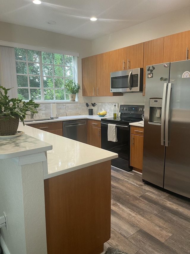 kitchen with dark wood-type flooring, stainless steel appliances, brown cabinetry, light countertops, and decorative backsplash