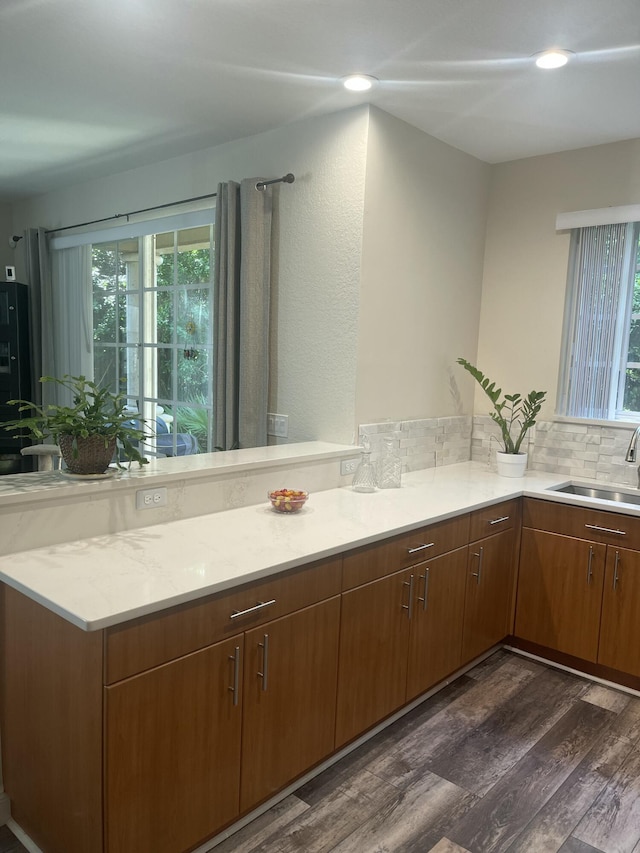 kitchen featuring dark wood-type flooring, decorative backsplash, recessed lighting, a peninsula, and a sink