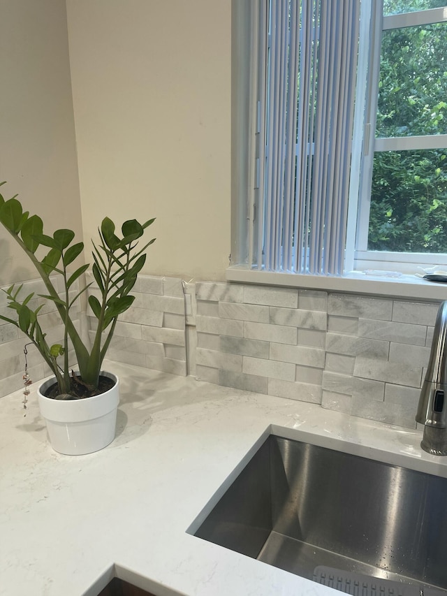 room details with light stone counters, tasteful backsplash, and a sink