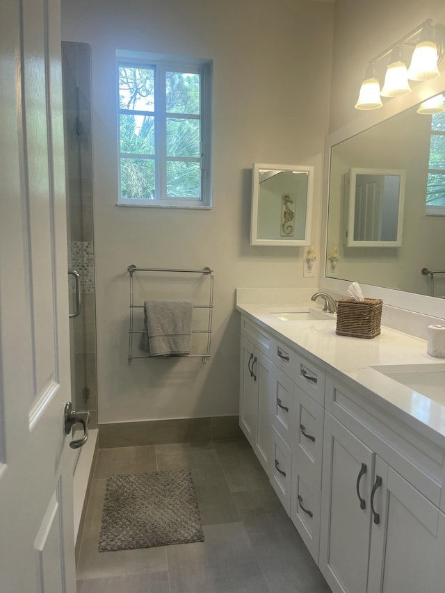 full bathroom with an enclosed shower, a sink, tile patterned flooring, double vanity, and baseboards