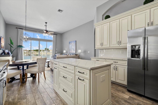 kitchen with tasteful backsplash, visible vents, wood finished floors, a notable chandelier, and stainless steel fridge