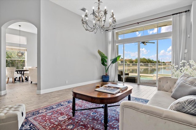 living area featuring arched walkways, a notable chandelier, visible vents, and wood finished floors