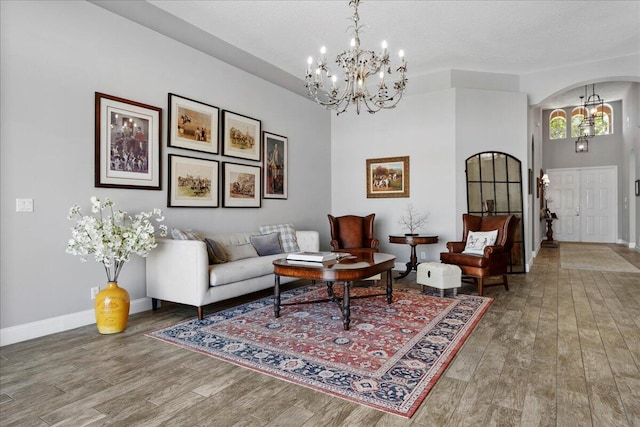 living room featuring a chandelier, arched walkways, and wood finished floors