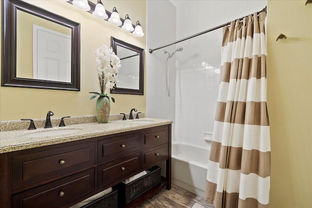 full bath with a sink, shower / tub combo with curtain, wood finished floors, and double vanity