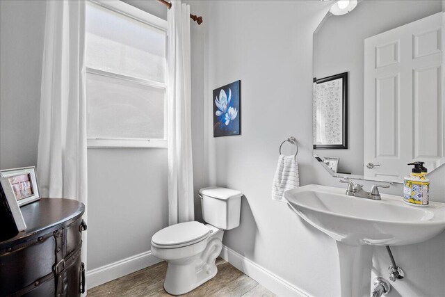 bathroom with toilet, baseboards, and wood finished floors