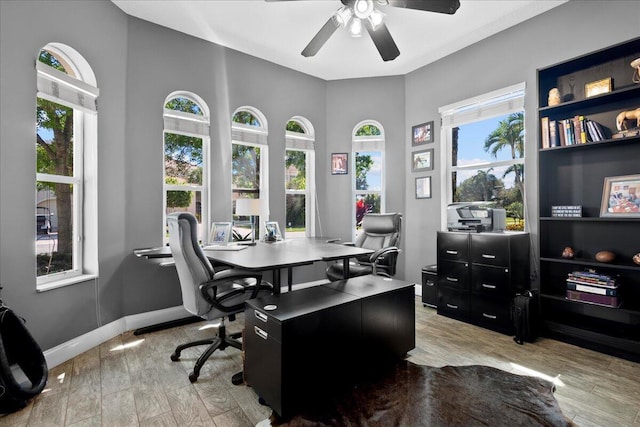 office featuring light wood-style flooring, a ceiling fan, and baseboards