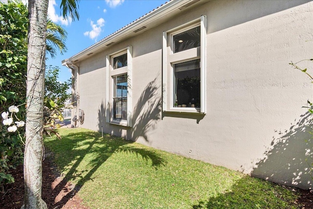 view of home's exterior with stucco siding and a lawn