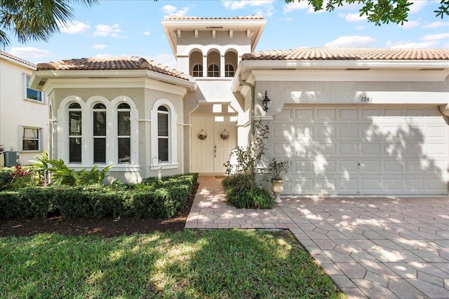 mediterranean / spanish-style house featuring decorative driveway, stucco siding, an attached garage, and a tile roof