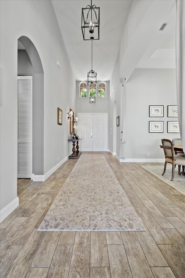 entryway featuring a notable chandelier, wood finish floors, baseboards, and visible vents