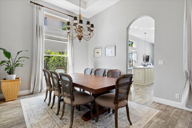 dining room with baseboards, arched walkways, a chandelier, and wood tiled floor