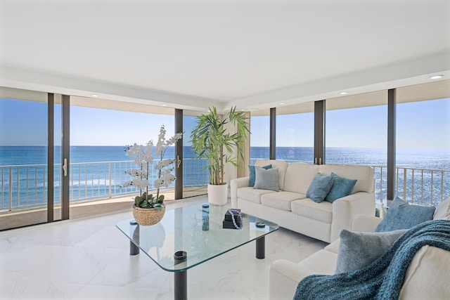 living room with a wealth of natural light, a water view, marble finish floor, and a wall of windows