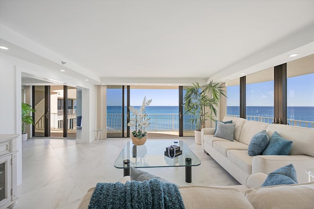 living room featuring recessed lighting, marble finish floor, a wall of windows, and a water view