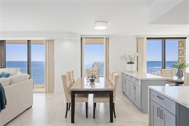 dining area with baseboards, a water view, and marble finish floor