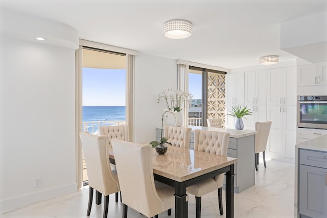 dining space with baseboards, marble finish floor, and a water view