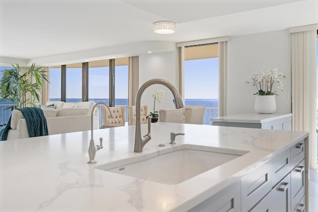 kitchen with a wealth of natural light, open floor plan, light stone countertops, and a sink