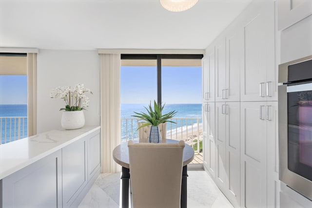 dining room featuring marble finish floor, expansive windows, and a water view