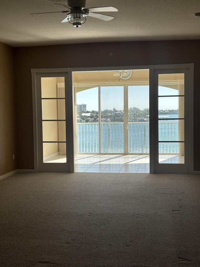 carpeted spare room featuring a textured ceiling and a ceiling fan