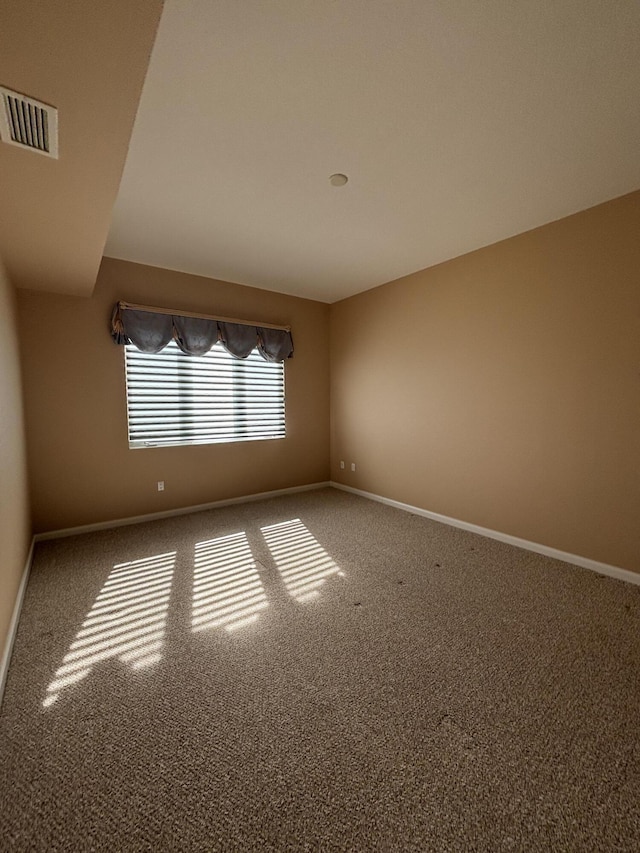 carpeted empty room featuring visible vents and baseboards